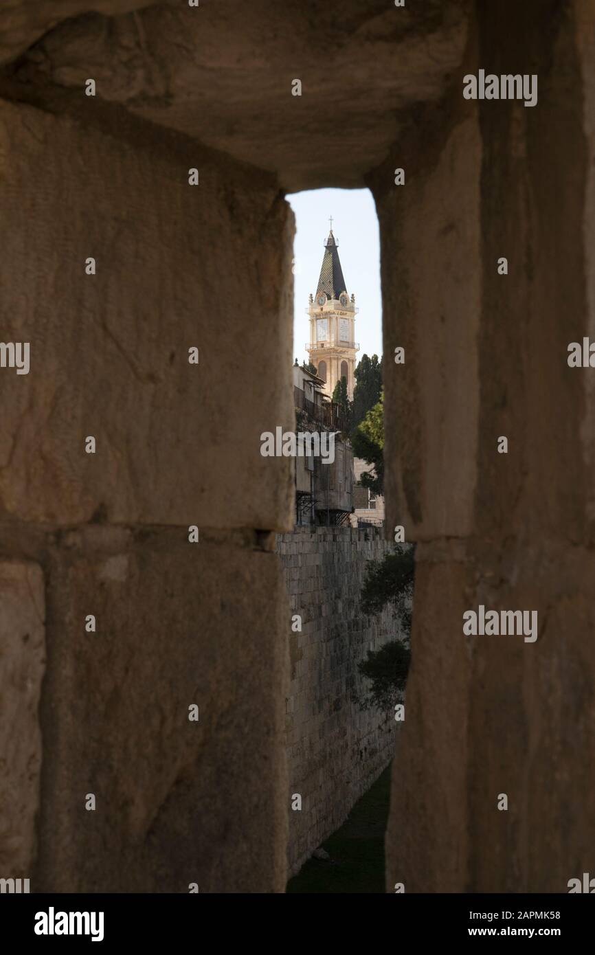 Clock tower of the monastery of Saint Saviour in the Christian quarter seen through an arrowslit in the rampart surrounding old city Jerusalem Stock Photo
