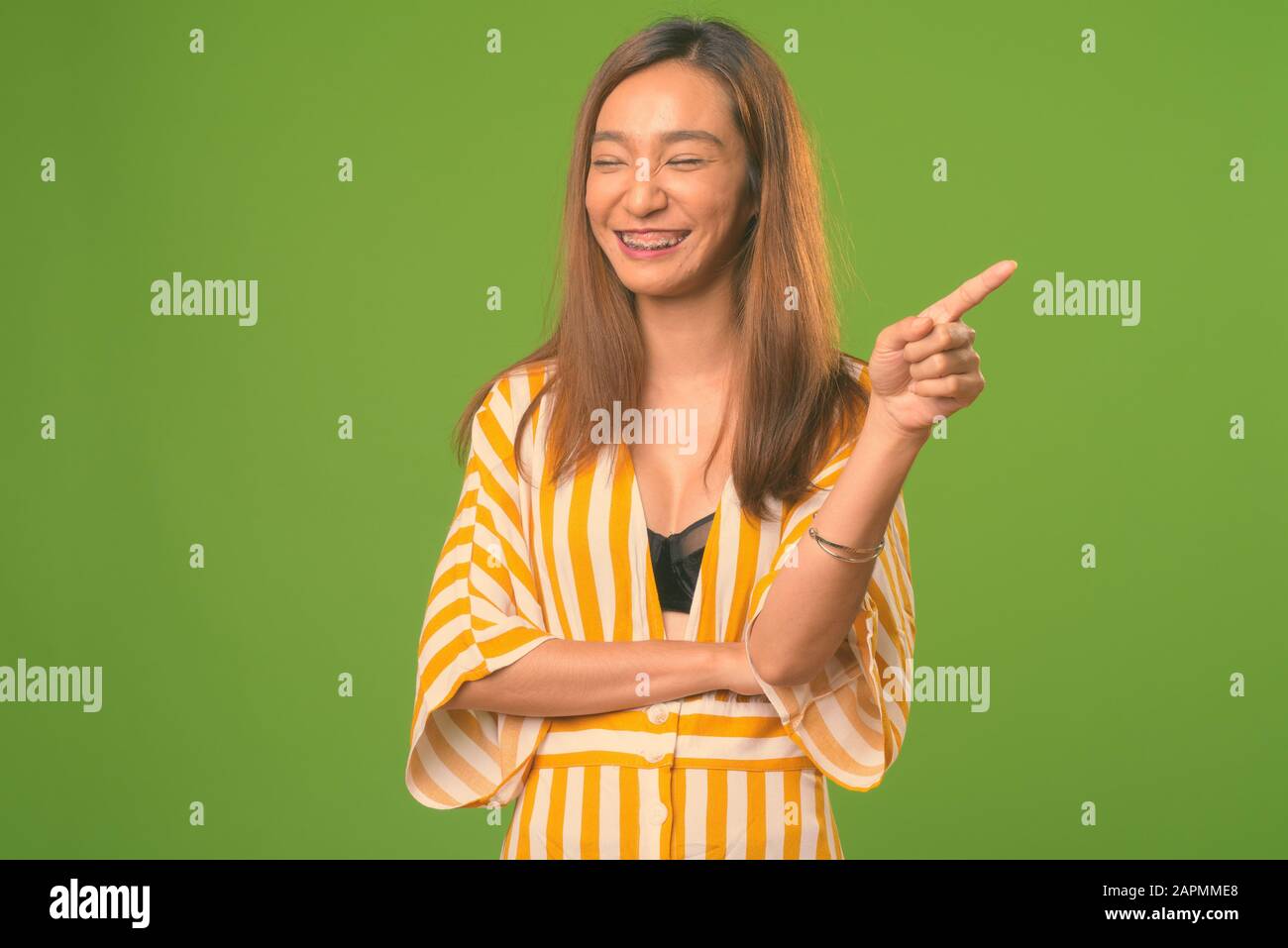 Young slim Asian woman against green background Stock Photo