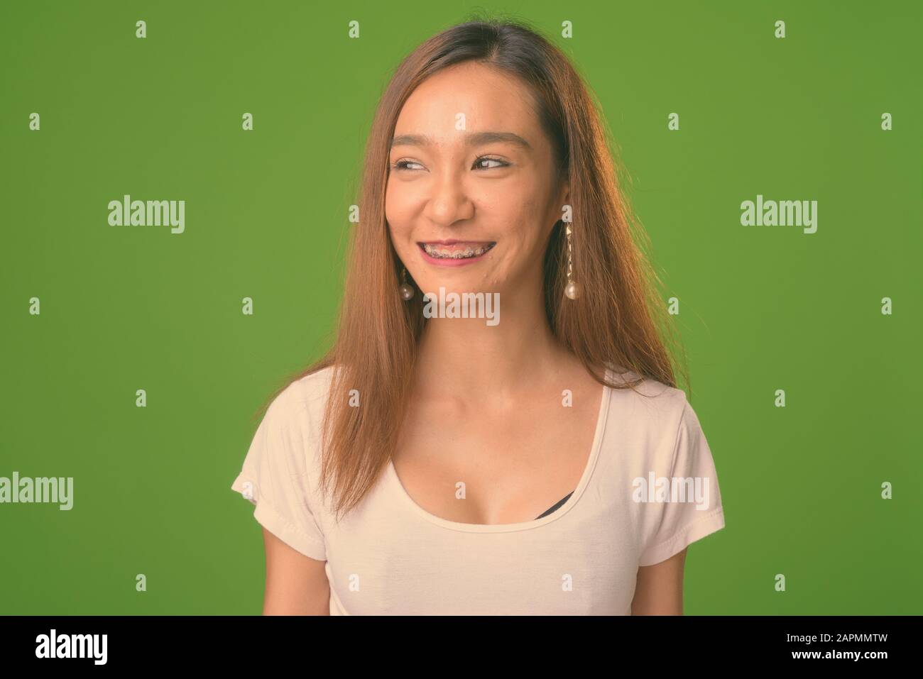 Young slim Asian woman against green background Stock Photo