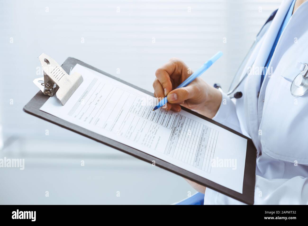 Woman doctor at work at hospital. Young female physician write