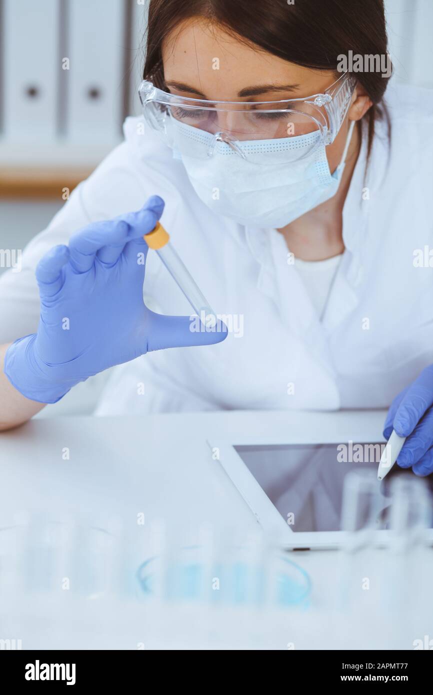 Close-up of professional female scientist in protective eyeglasses ...