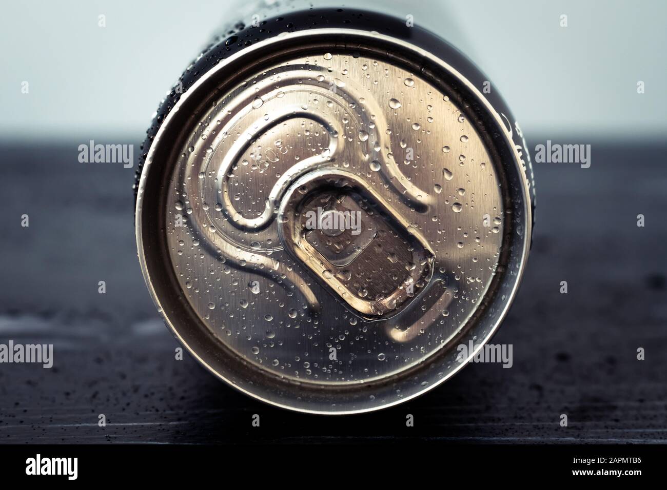 Metal drink can with water drops. Shiny cola can close-up. Golden bottle of beverage, lid of packaging of soda, tonic. Top view Stock Photo