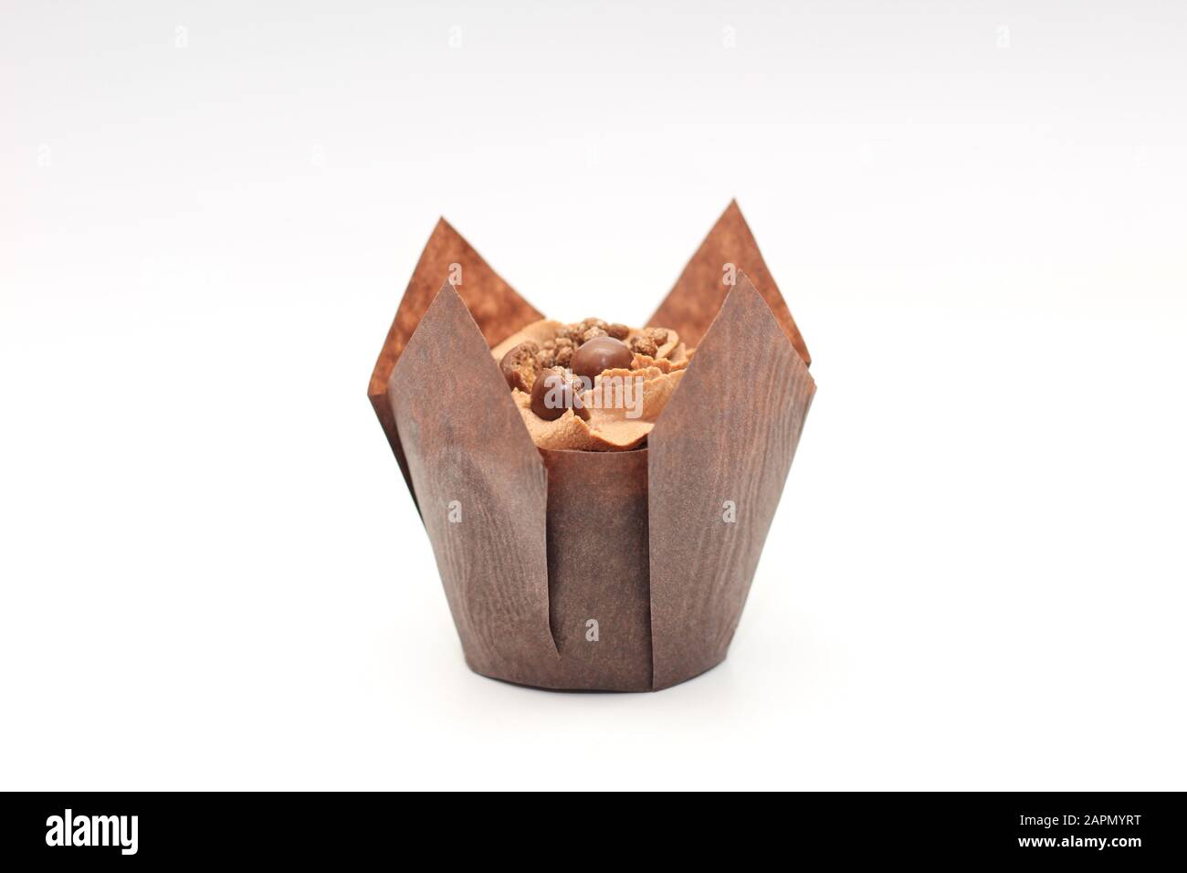 Isolated chocolate cupcake with cream top and crispy topping in paper ...