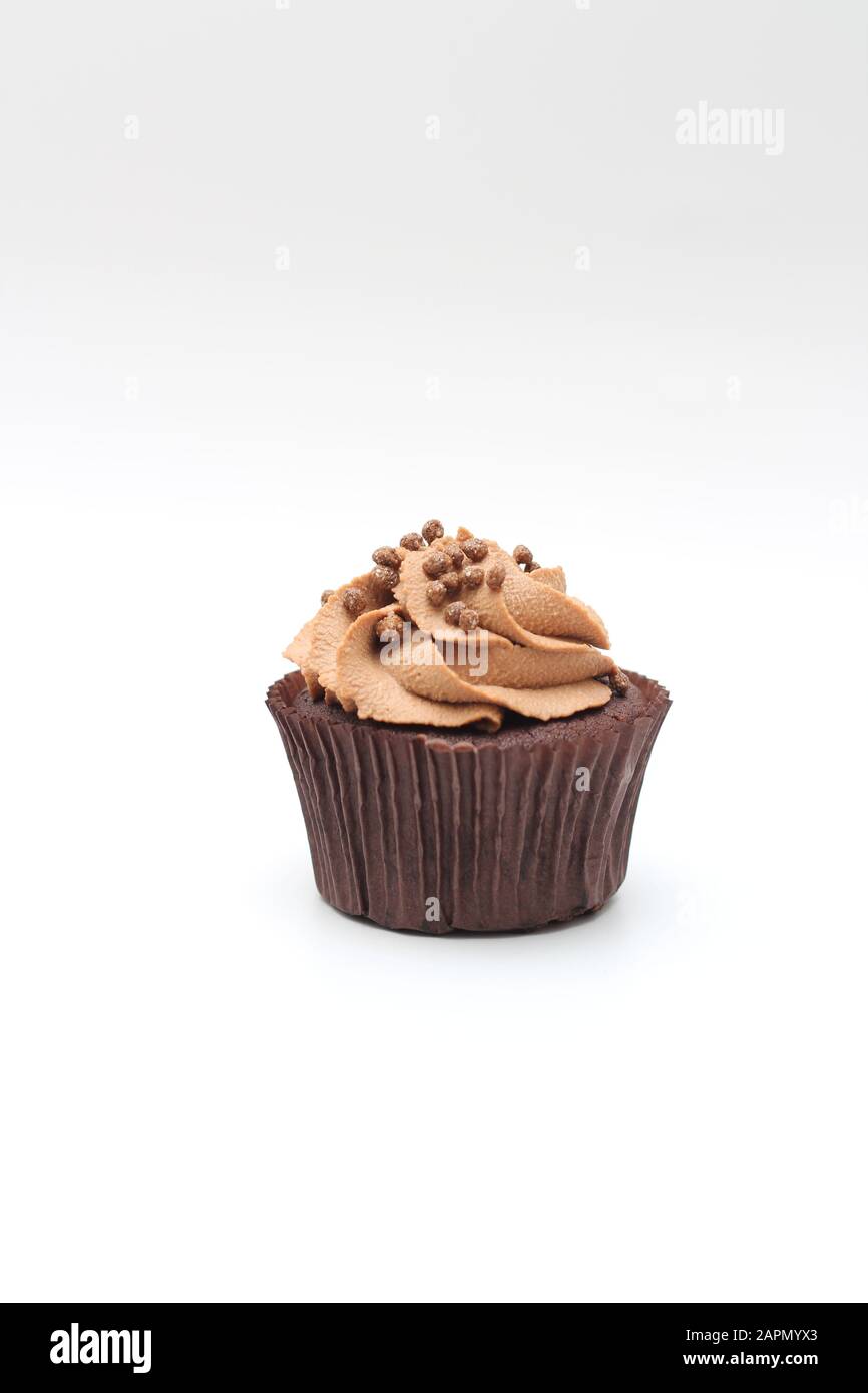 Isolated chocolate cupcake with cream top and crispy topping on a white ...