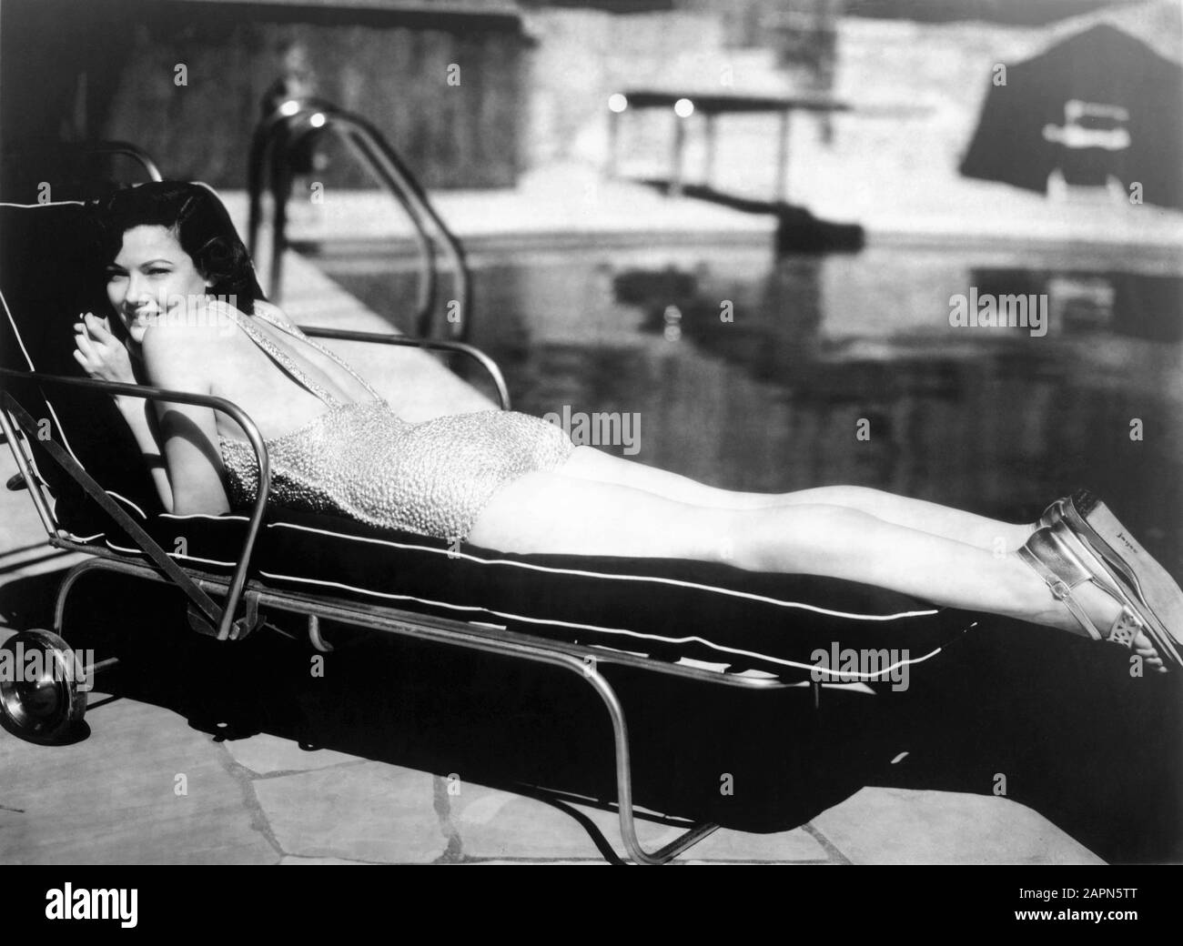 GENE TIERNEY 1940 first publicity photo in swimsuit on sun lounger by swimming pool Twentieth Century Fox Stock Photo