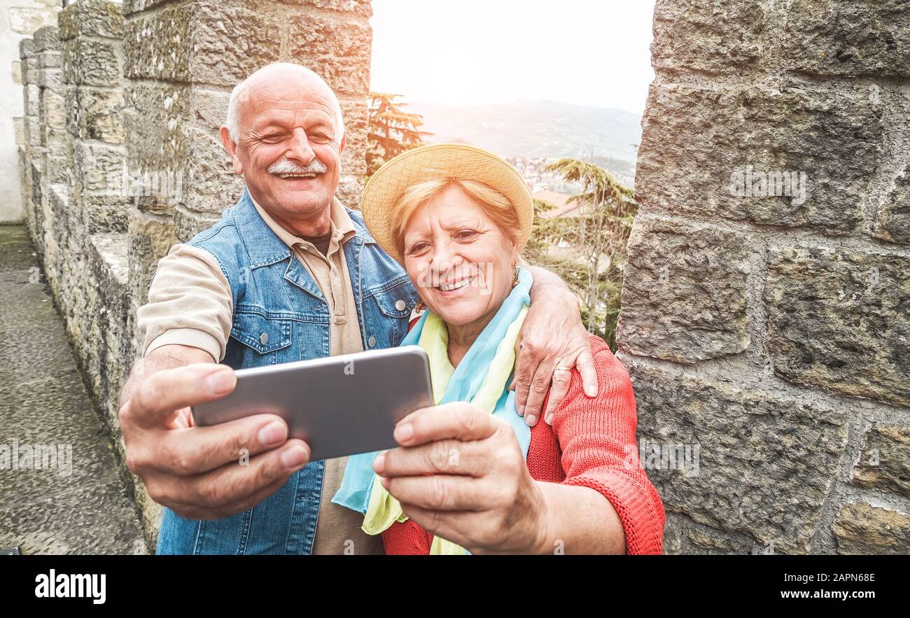 Senior couple taking a selfie inside castle on tour vacation - Mature husband and wife having fun with technology trends - Love, relationship and joyf Stock Photo