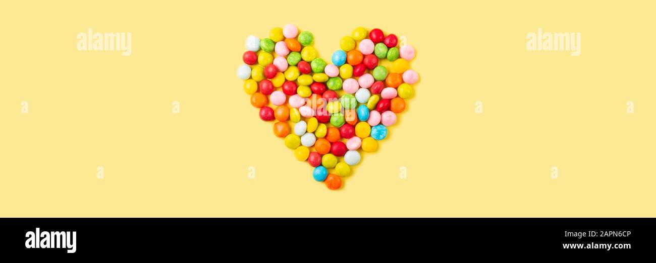 Old fashion pale multi colored candy heart background on yellow. Banner ...