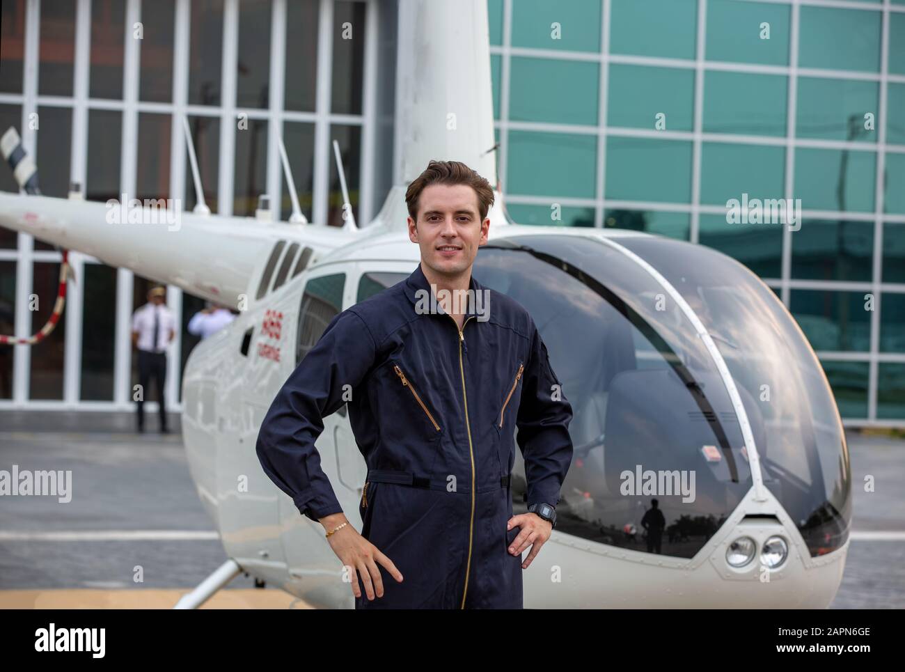 Commercial man pilot in technician suit standing in front of helicopter after check and maintenance engine Stock Photo