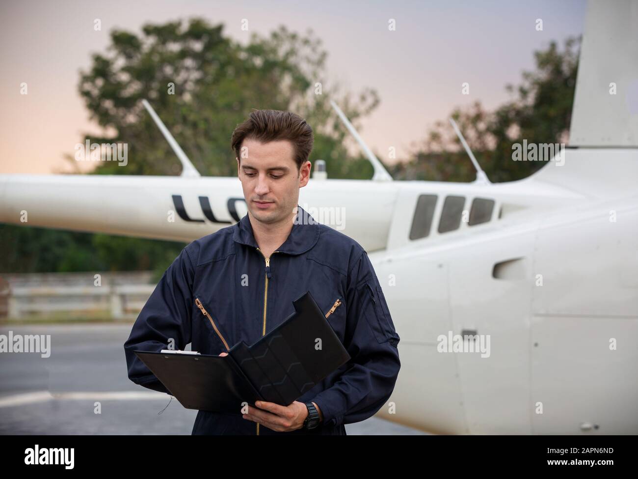 Commercial man pilot in technician suit standing in front of helicopter after check and maintenance engine Stock Photo