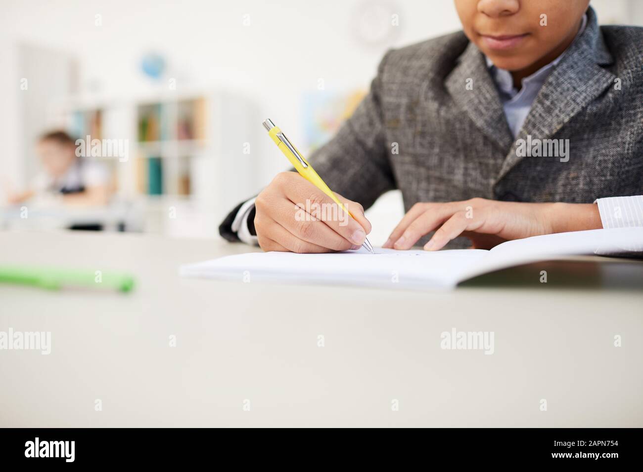 Close-up of African schoolboy sitting at the table and making notes in notebook during exam Stock Photo