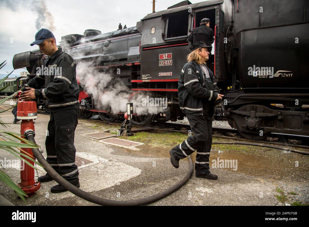 Nova Gorica, Slovenia, November 4, 2017: Railway personnel tends to a 1944 Henschel & Son German steam engine at the Nova Gorica train station. The locomotive is one of two that pull an old museum train on the Bohinj railway line (Transalpina) built from 1900 to 1906 as the shortest connection of the Austro-Hungarian Empire with the Adriatic Sea in Trieste (Italy). Stock Photo