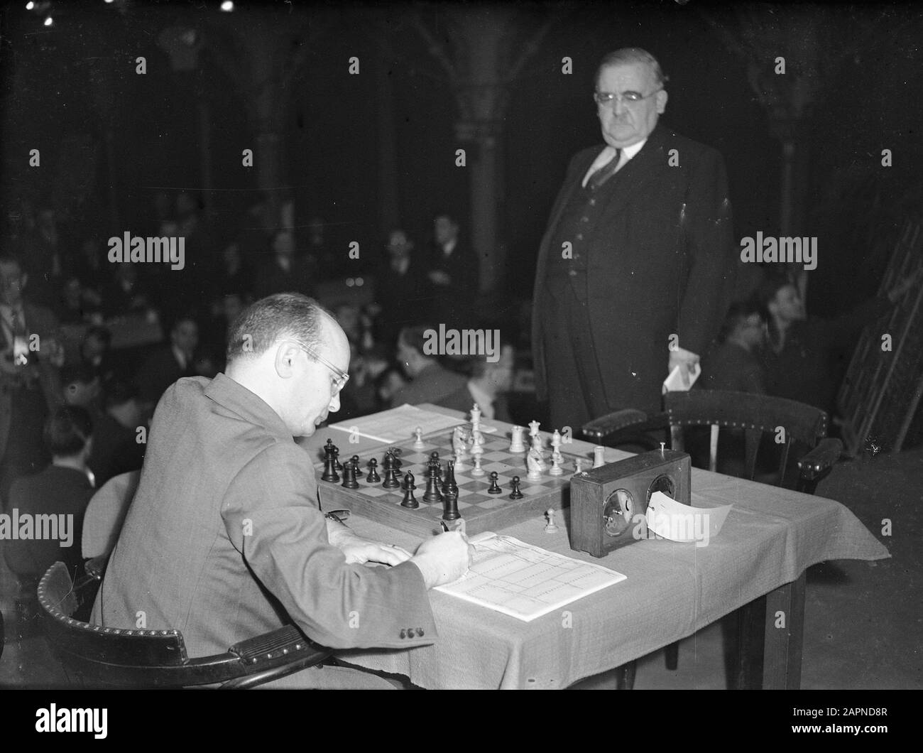 World Chess Championship. Samuel Reshevsky notes a move and competition  leader prof. dr. Vidmar watches Annotation: Location Grote Zaal Haagse  Zoological Date: 26 February 1948 Location: The Hague, Zuid-Holland  Keywords: chess, sport