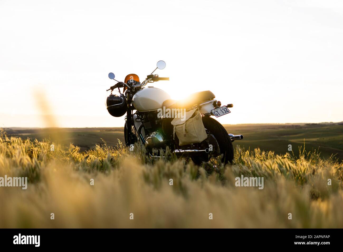 Classic Motorcycle on on a hill at sunset in a country field Stock