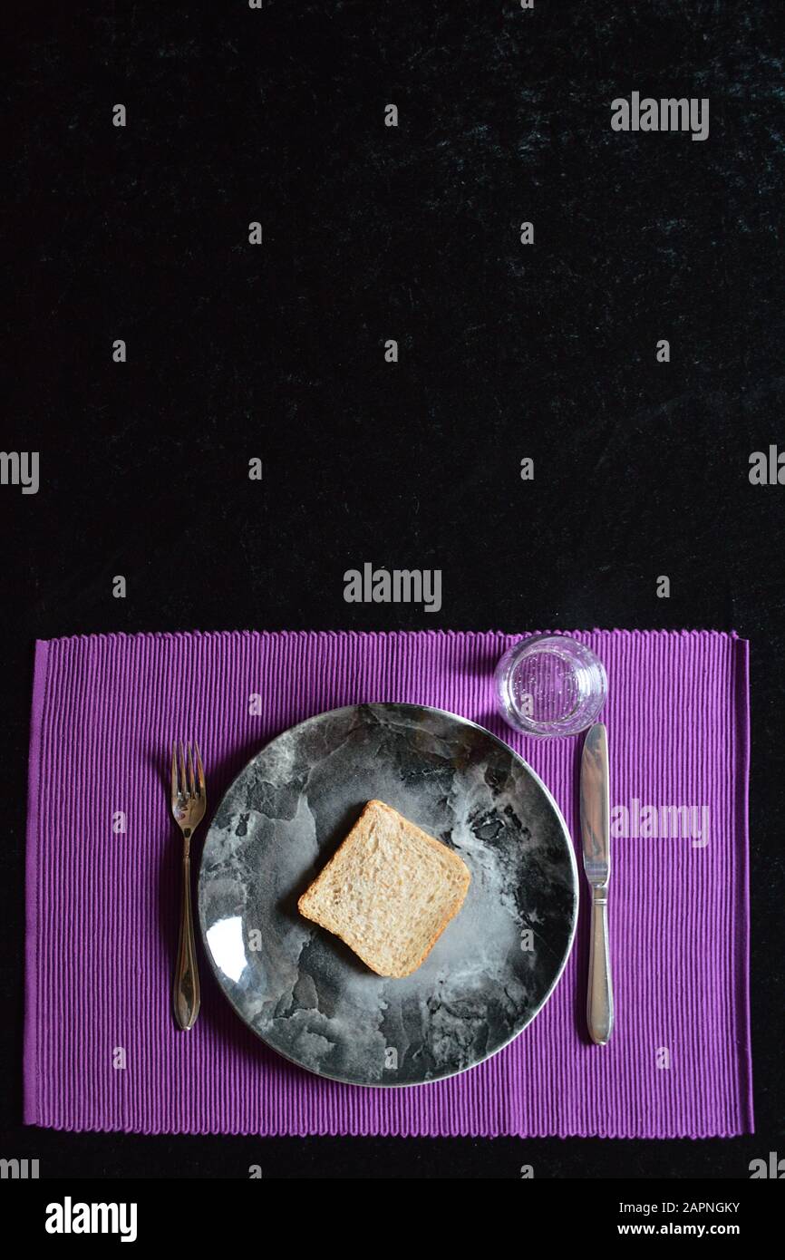 reduced meal in Lent with a slice of bread on a plate and a glass of water Stock Photo