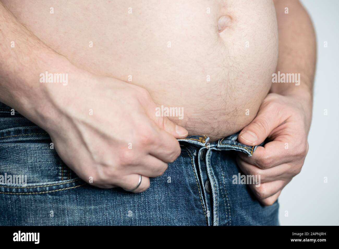 Man with big belly hardly button up his pants Stock Photo - Alamy