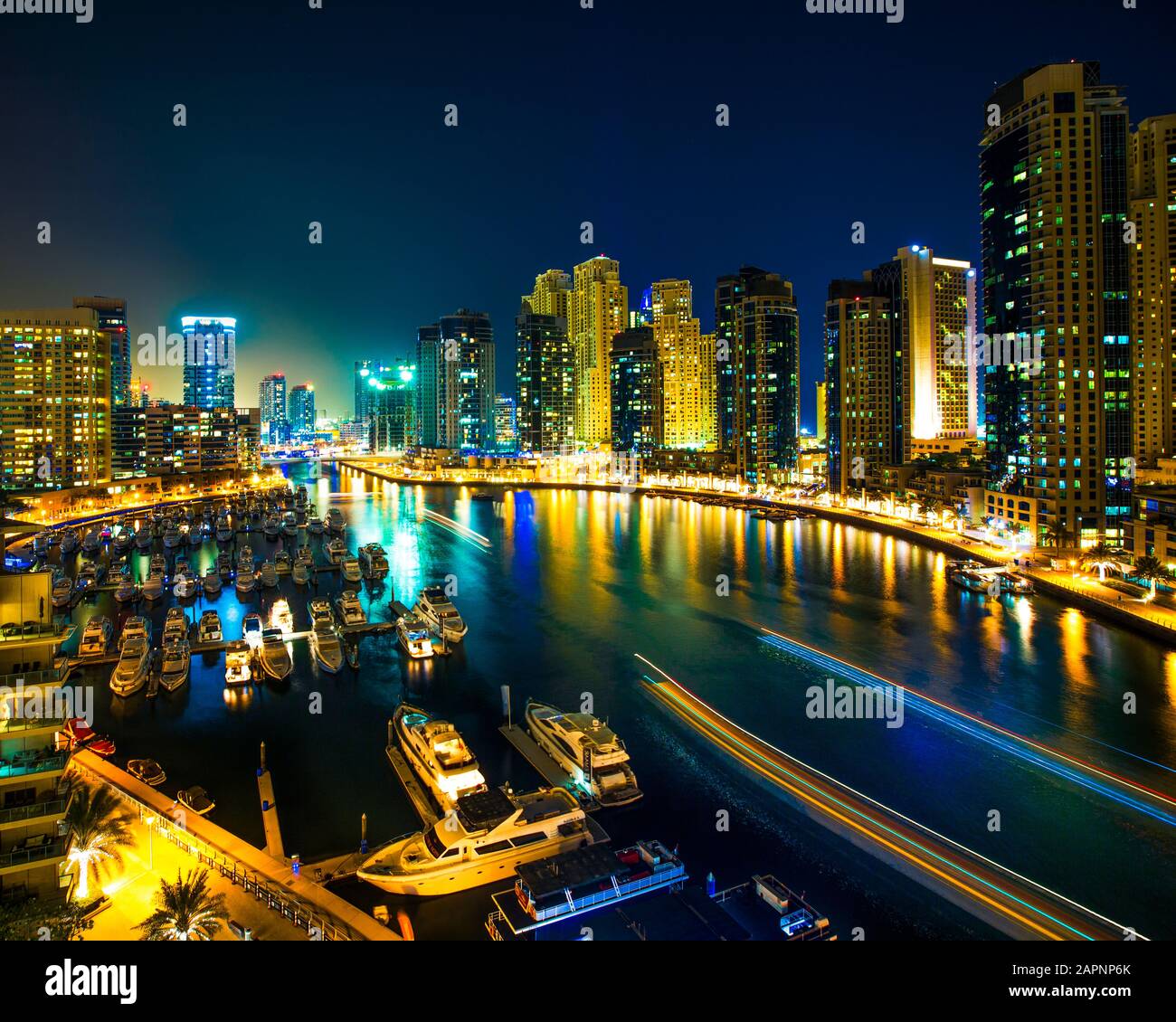 Night scene of city skyline and boats moored at harbour, Dubai Stock Photo