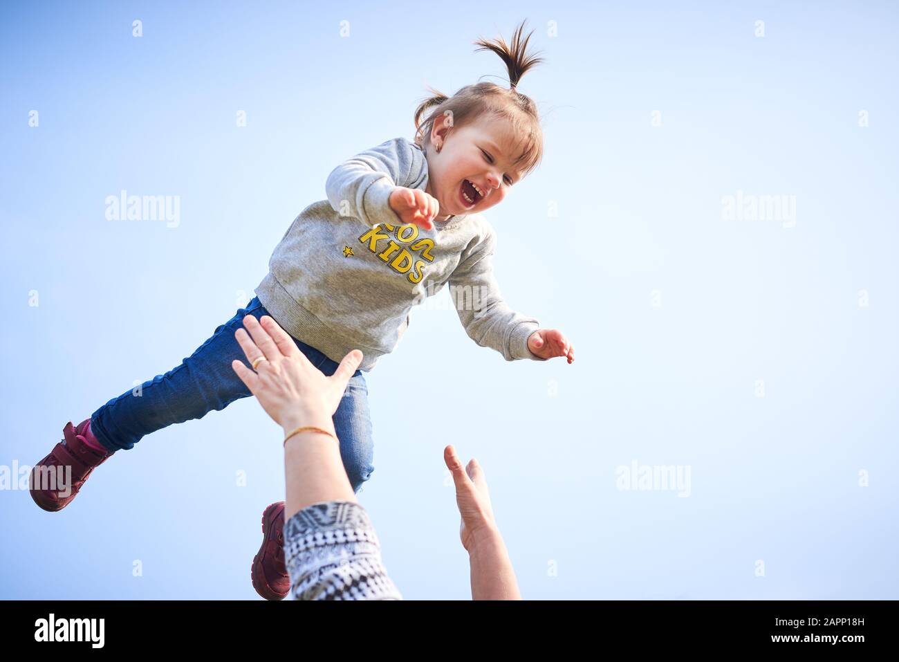 Mother playing with her daughter, throwing little girl into the air