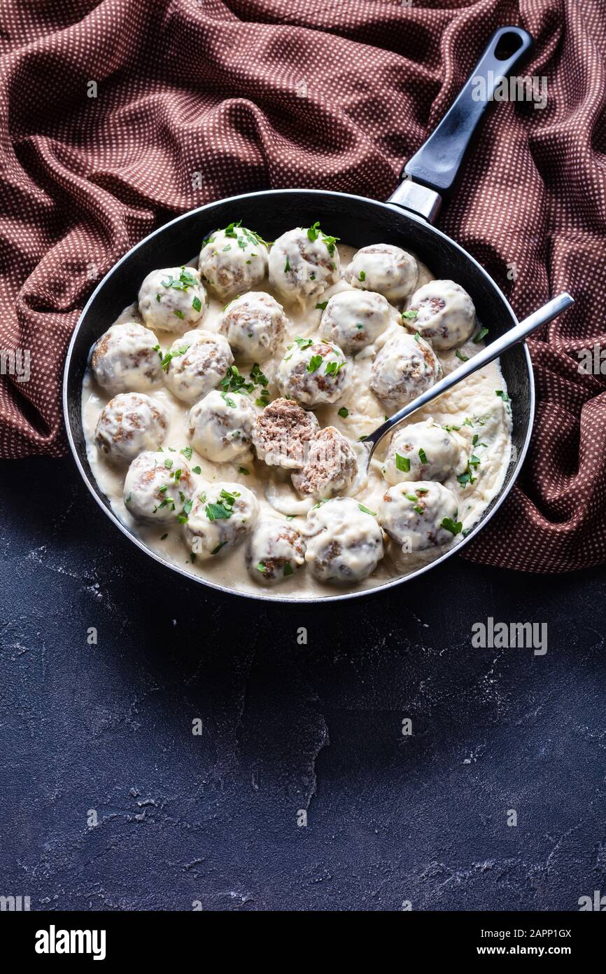 classic Swedish meatballs with creamy sauce and parsley in a skillet on a concrete kitchen table, vertical view, copy space Stock Photo