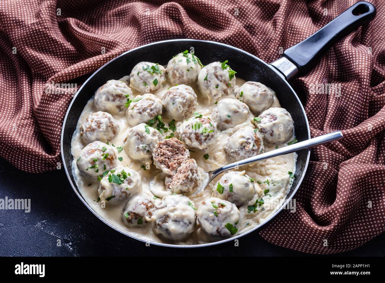 classic Swedish meatballs with creamy sauce and parsley in a skillet on a concrete kitchen table, horizontal view from above Stock Photo
