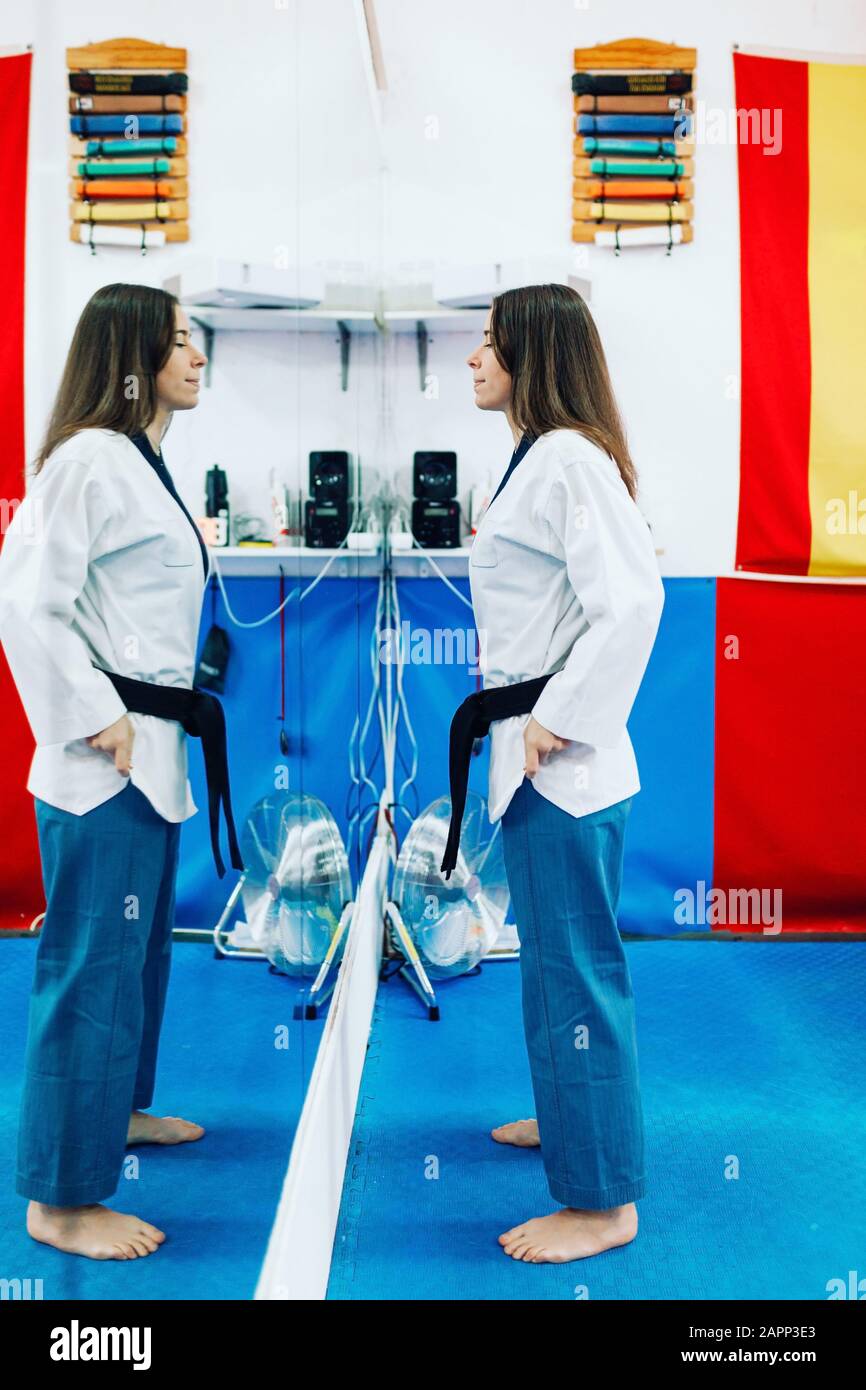 Young woman dresses in her taekwondo suit in front of the mirror Stock Photo