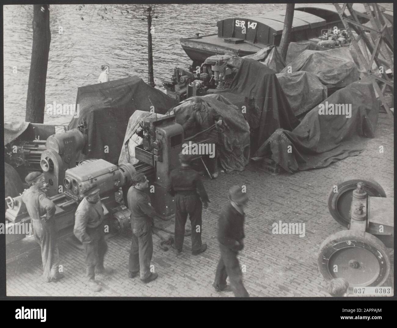 Machines and parts are unloaded in a port [recuperation Germany?] Date: 1945 Keywords: workers, ports, machinery, shipping Stock Photo
