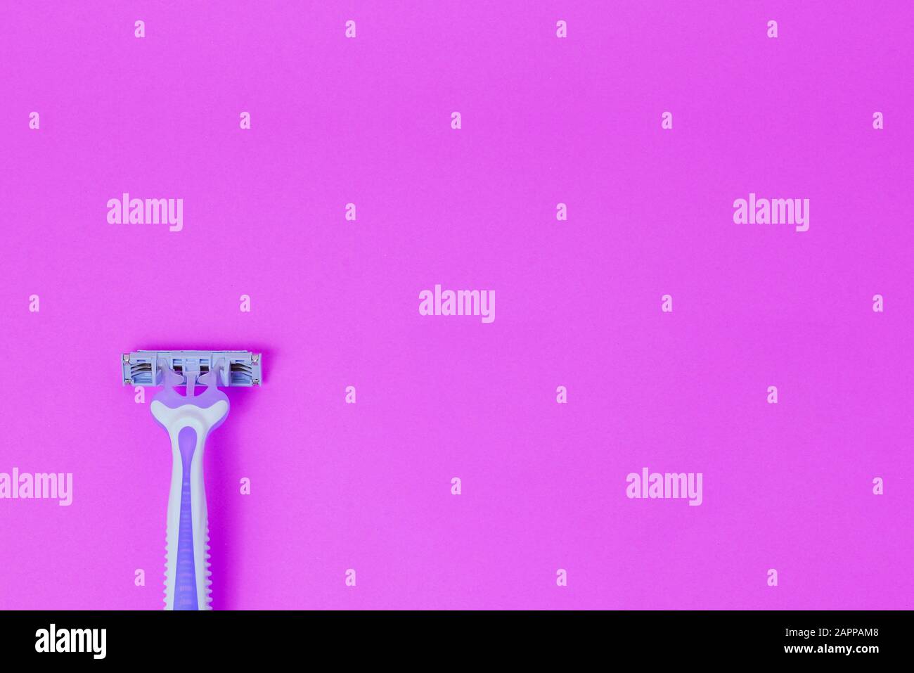 Disposable female razor on a purple background. A tool to remove hair from the skin. Female