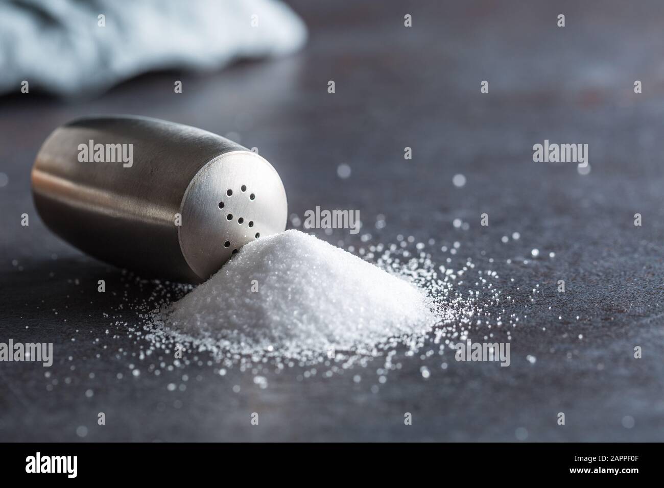 Spilled salt with staniless salt shaker - Closeup Stock Photo