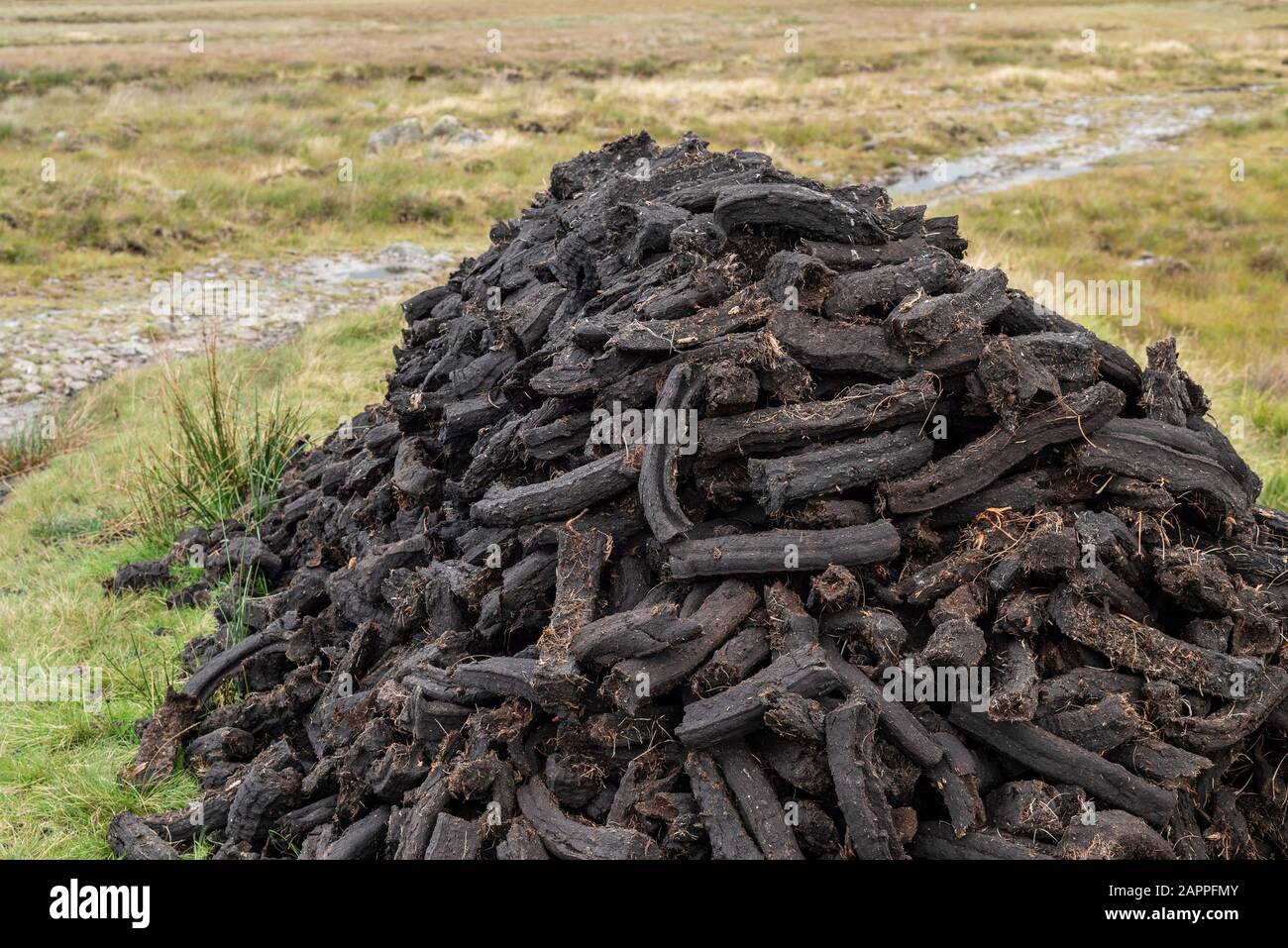 A stack of dried sods of peat or turf in August, awaiting collection for use as fuel having been cut and dried on a bog in County Mayo, Ireland Stock Photo
