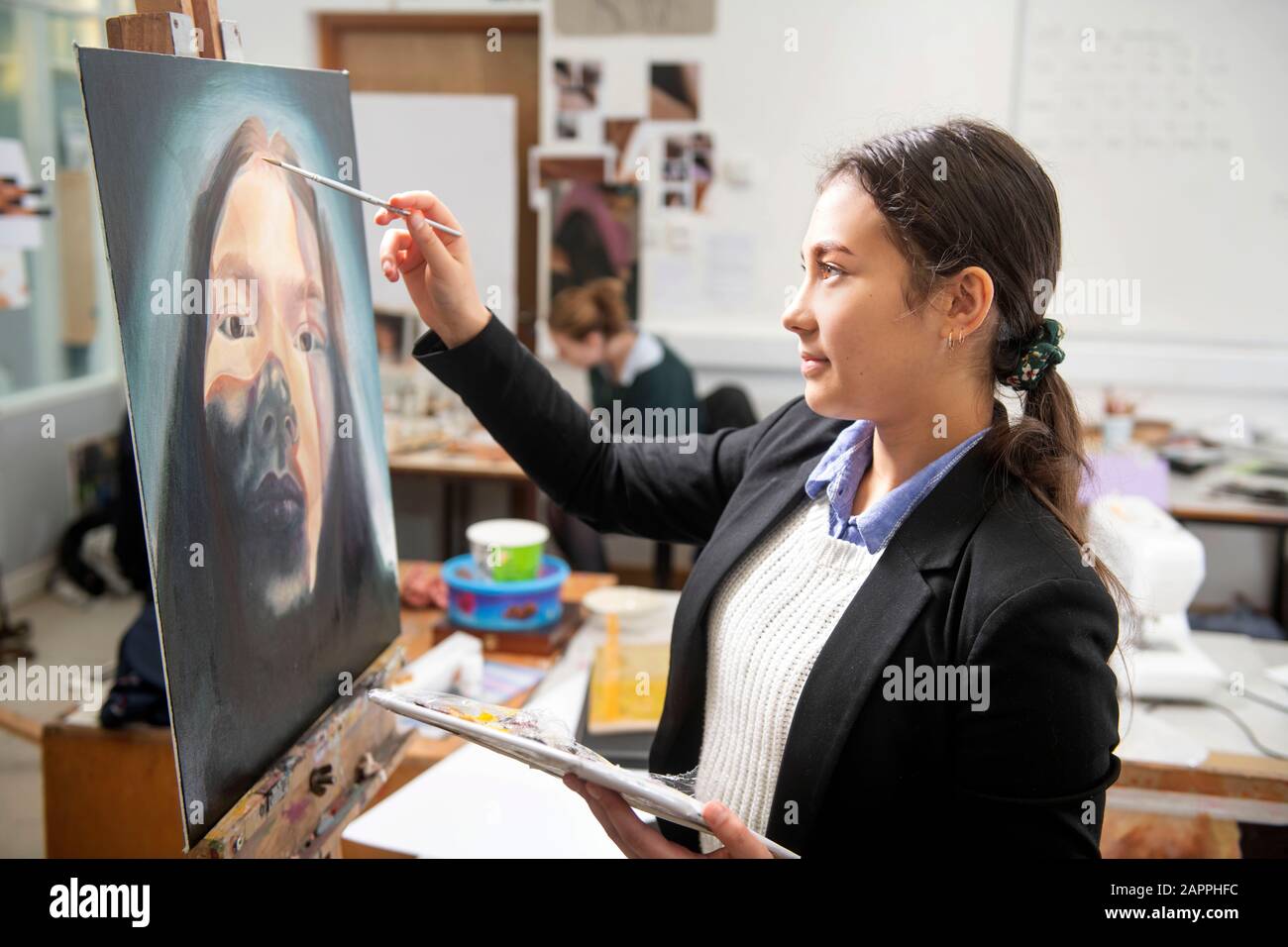 An ‘A’Level art student painting in a secondary school, UK Stock Photo