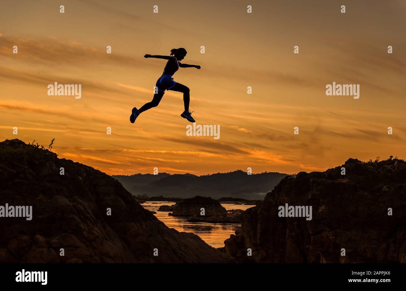 Woman jump through the gap between hill.woman jumping over cliff on sunset  background,Business concept idea Stock Photo - Alamy