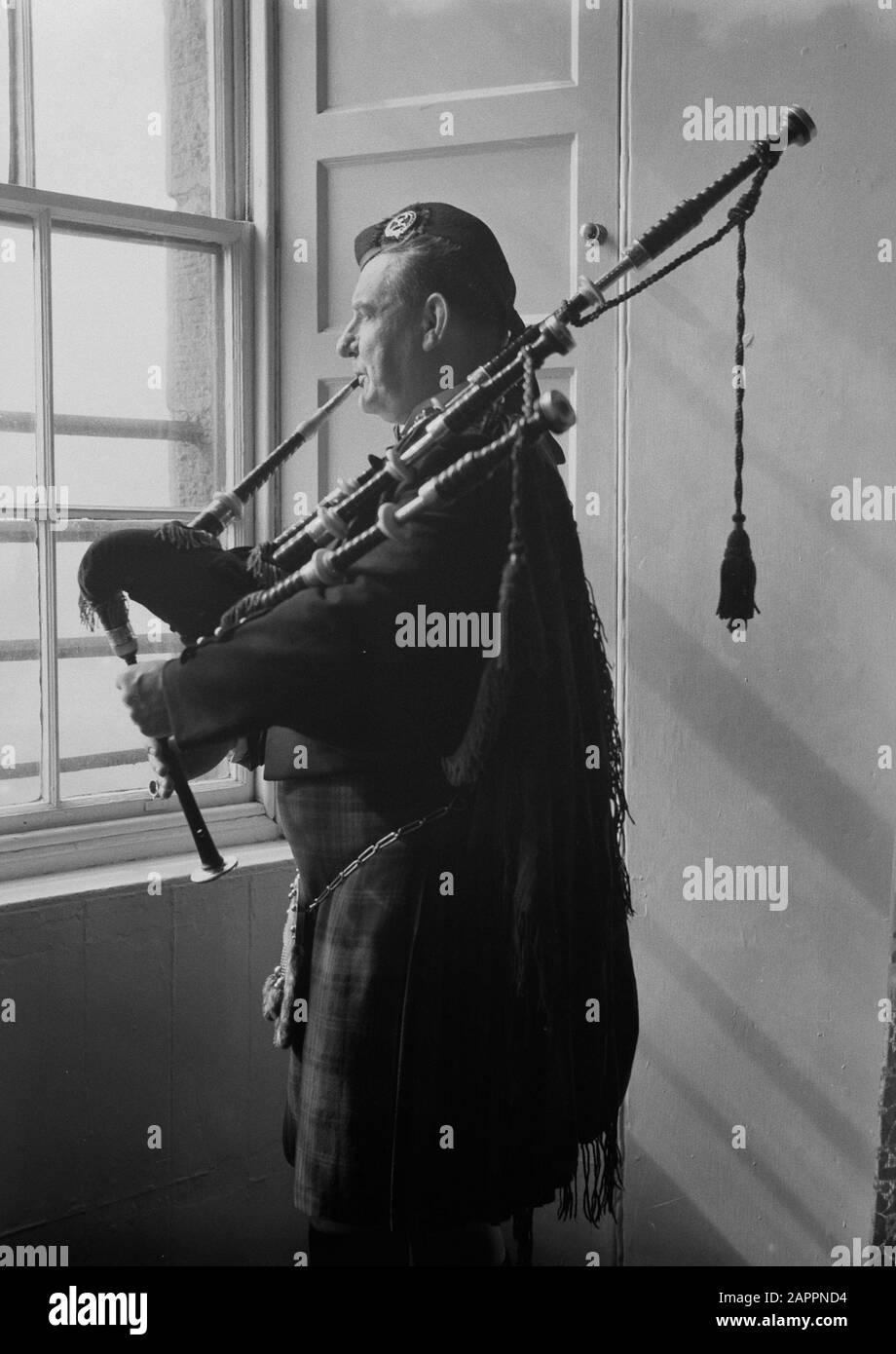 Scotland - Barracks Edinburgh Castle  William Ross plays his bagpipes, standing in front of the window Annotation: Pipe Major William Ross (1878-1966) taught at the Army School of Piping at Edinburgh Castle. Date: 1934 Location: Edinburgh, Great Britain, Scotland Keywords: bagpipes, interiors Personal name: Ross, William Stock Photo