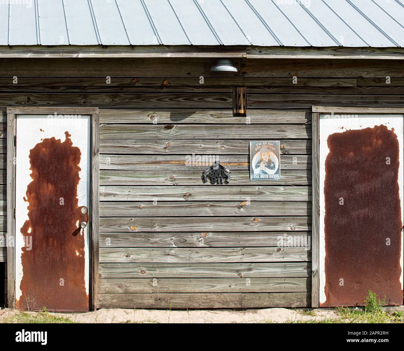 Side of an old wooden siding barn. Tin roof, barn light, two signs and
