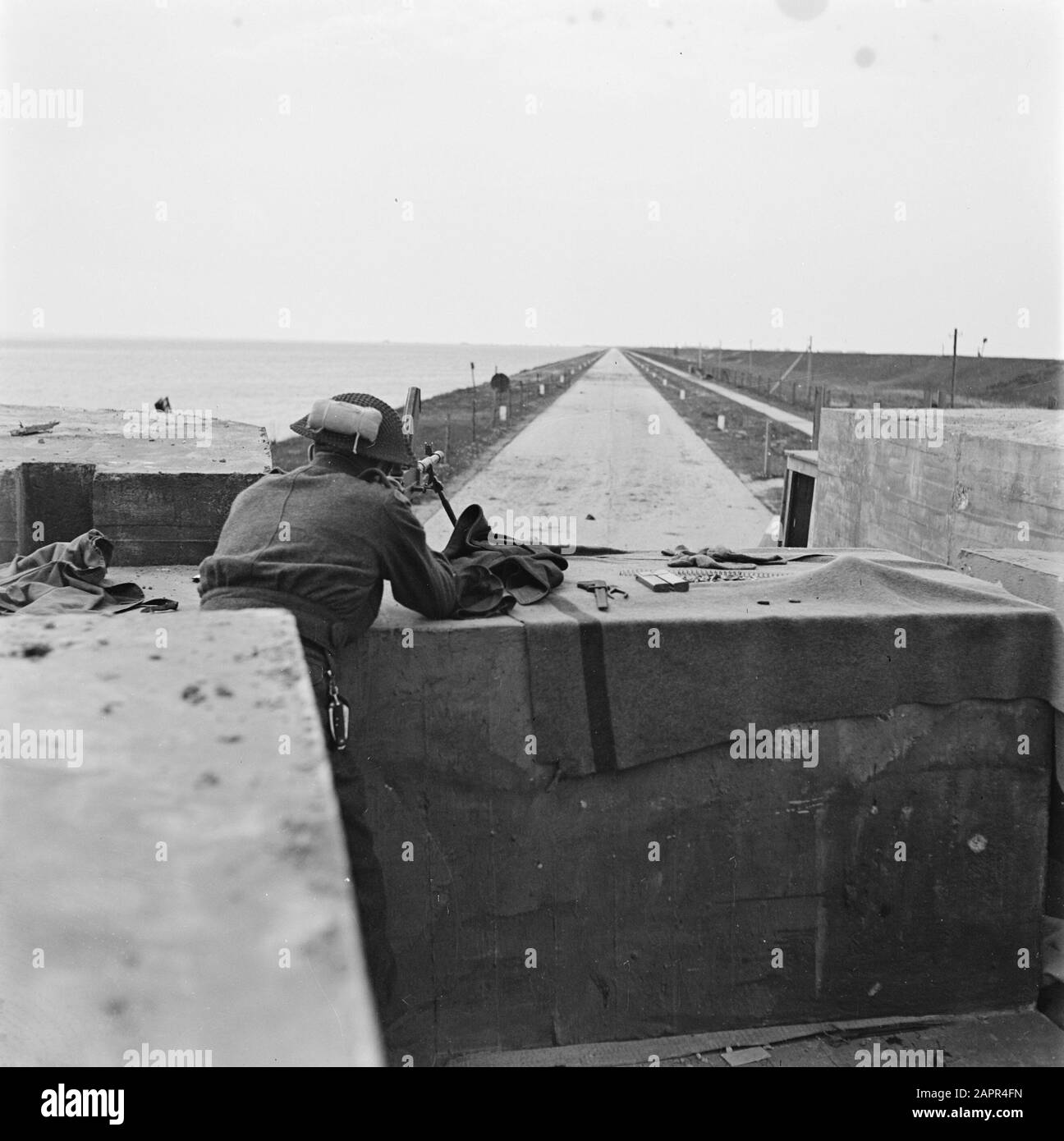Front North-East Netherlands: Groningen-Friesland  With the liberation of North Netherlands, the Allied troops got their hands on the positions at the Afsluitdijk near Zurich (Friesland). They can now oversee the German theses. The enemy is still nesting on the Kornwerderzand strip. Canadian military standing behind a Brenmachine-gun on the Kop van de Afsluitdijk (towards Kornwerderzand). Date: April 18, 1945 Location: Afsluitdijk, Friesland Keywords: military, weapons Stock Photo