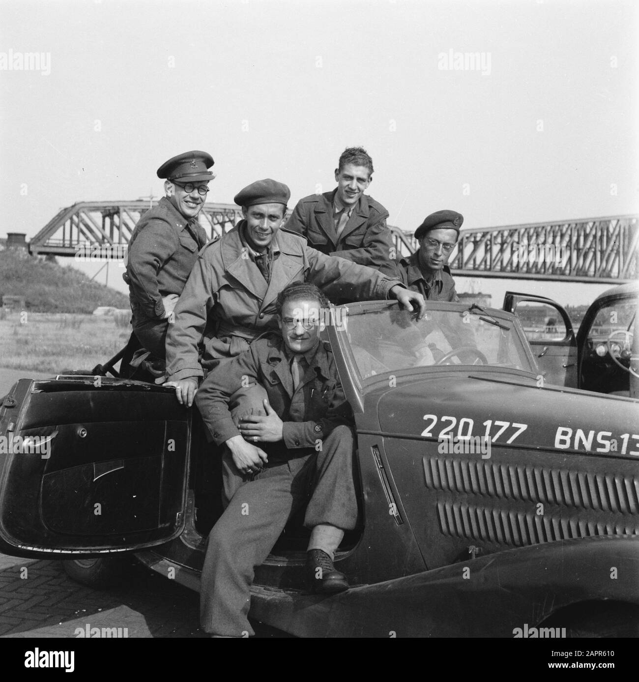 [Dutch? war correspondents pose in their car. In the background a bridge] Date: 1945 Keywords: gasoline, journalists, World War II Stock Photo