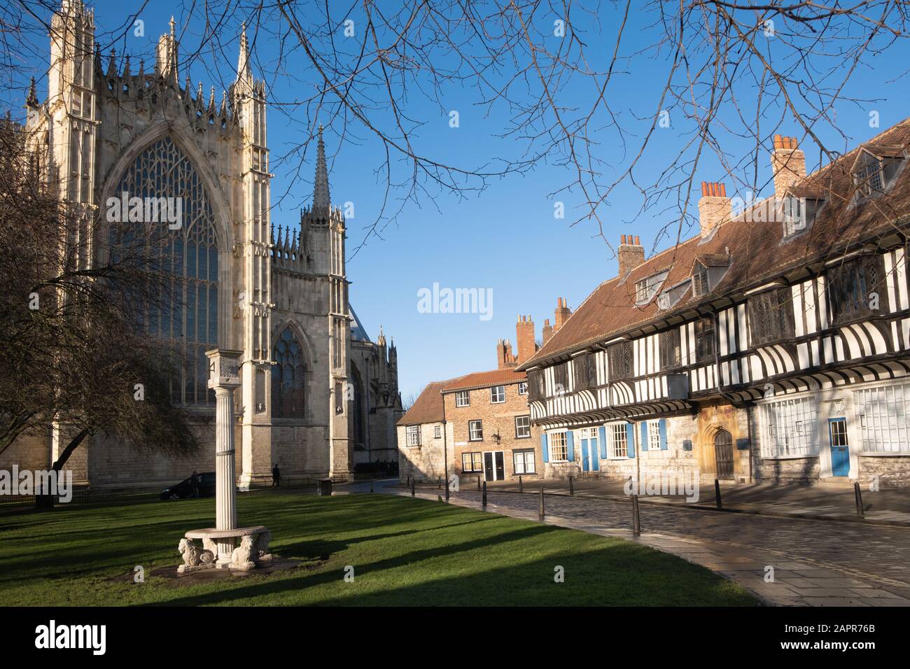 York Minster yard, an ancient sundial on top of a column, half-timbered houses and the east front of the great cathedral Stock Photo
