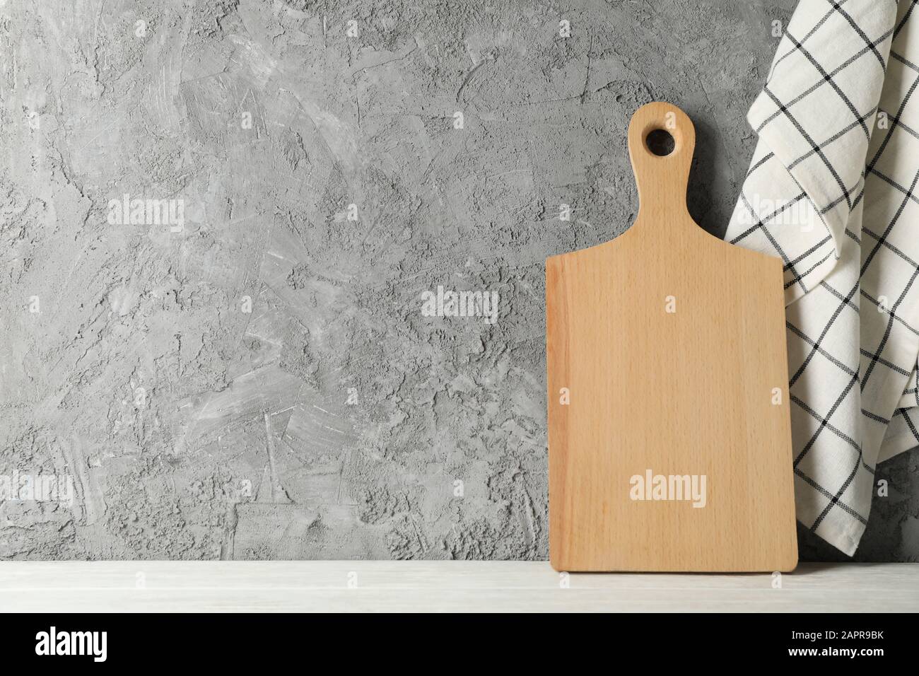 Wooden board on white table against gray background, space for text Stock Photo