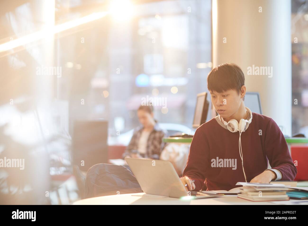 Asian college student using laptop computer while sitting at the table ...