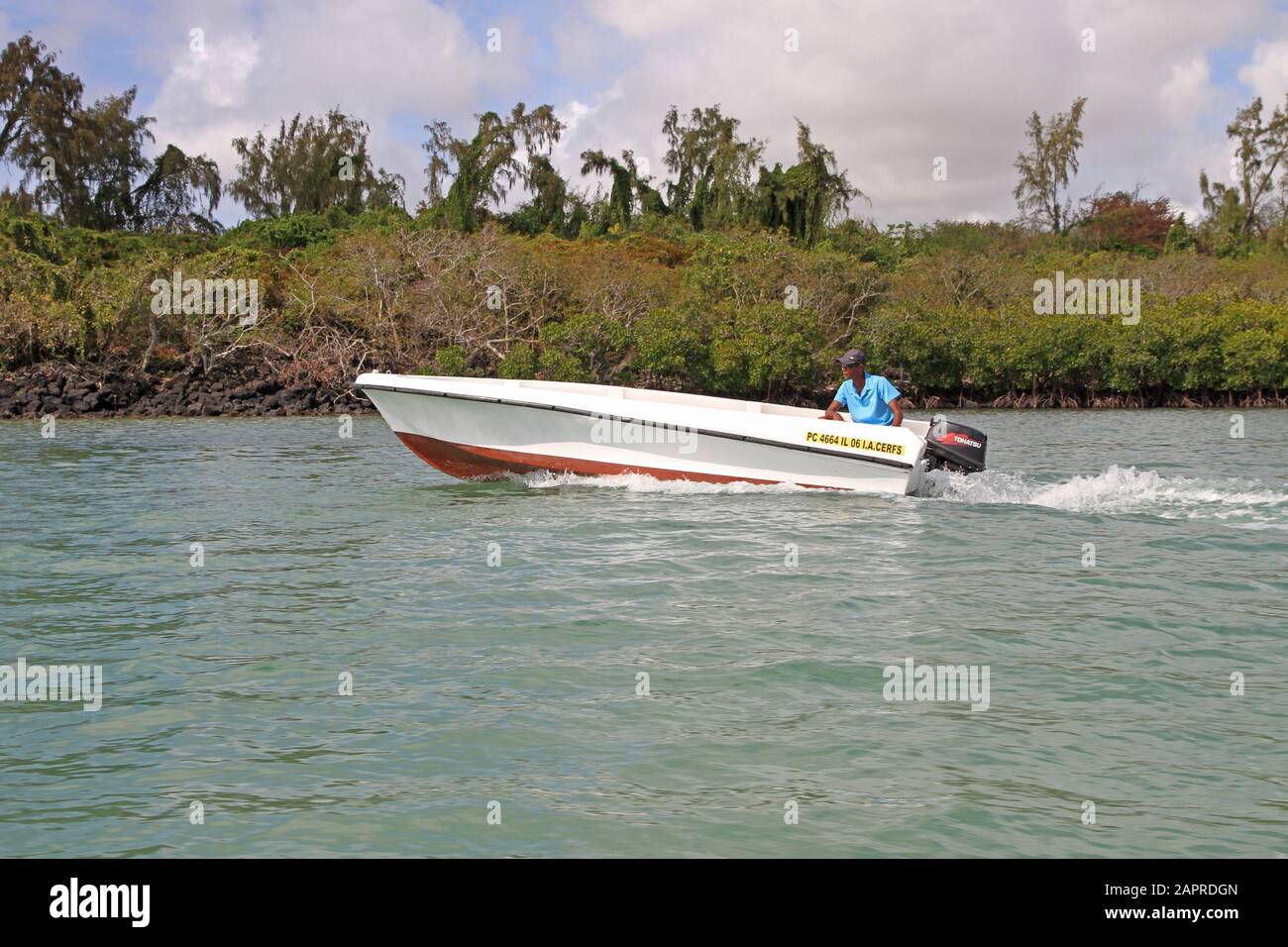 Mangroves and man in motor boat off the Coast of Mauritius. Stock Photo