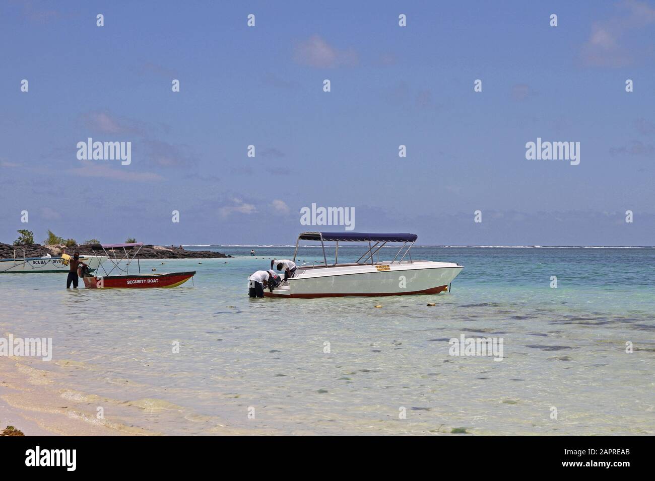 Boats and people on the beach in the water on the coast of Mauritius. Stock Photo