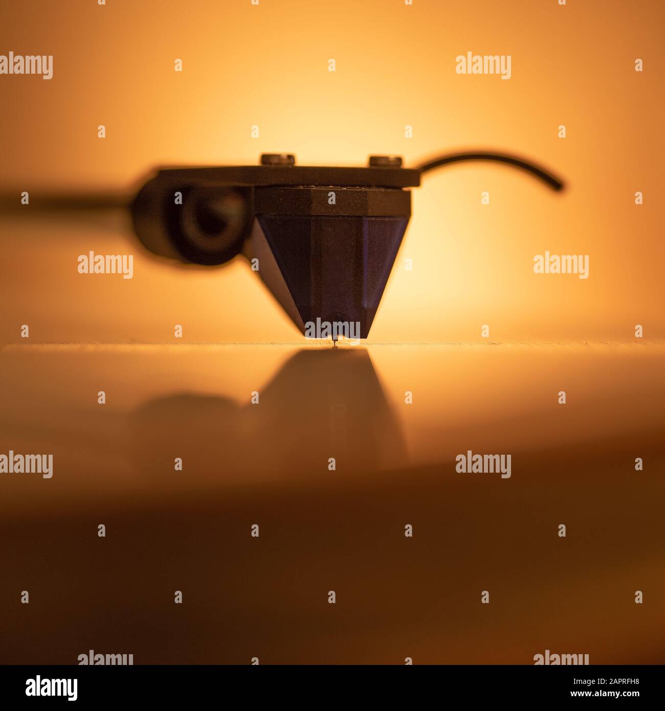 Closeup shot of a gramophone needle with an orange background Stock Photo