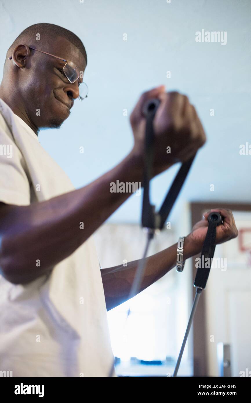 Young man of African descent exercising for arm and core strength with a piece of equipment Stock Photo
