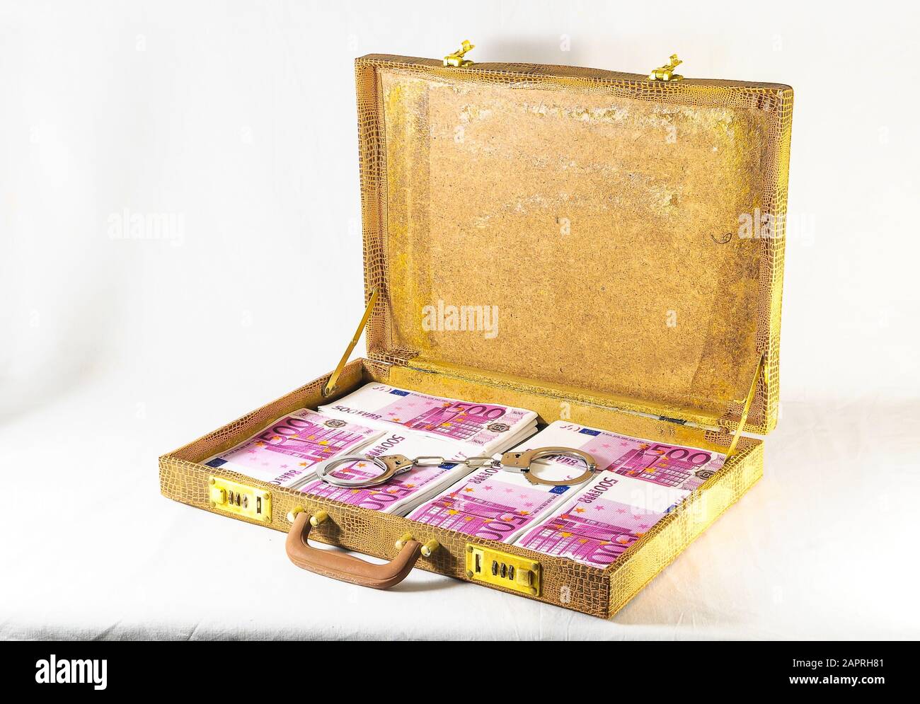 Landscape shot of a golden briefcase with a silver handcuff placed at