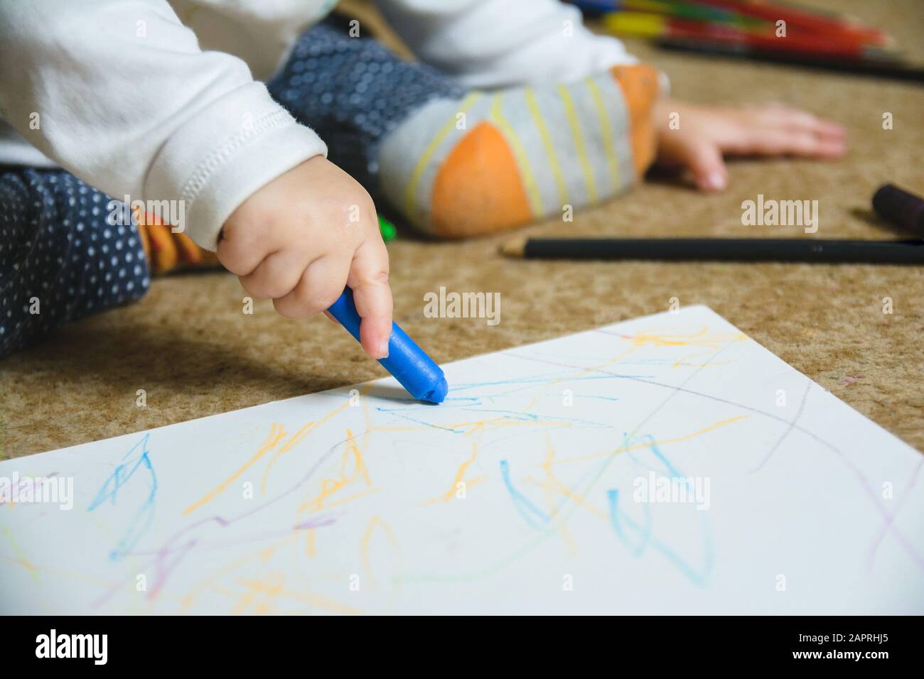 Small baby drawing with a blue crayon on a paper Stock Photo - Alamy