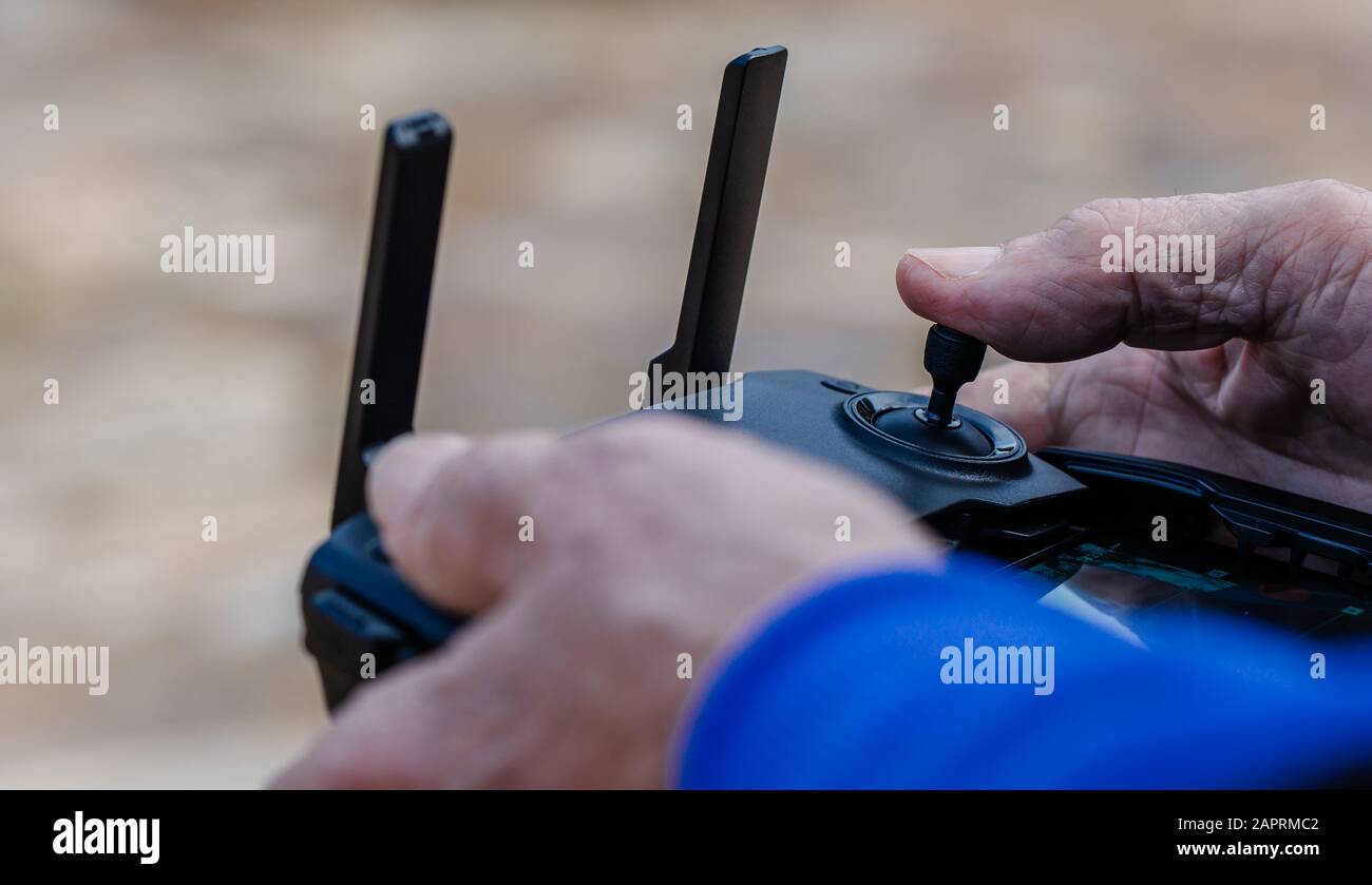 Close-up of an old man with his finger on the joystick operating a drone using a remote control Stock Photo