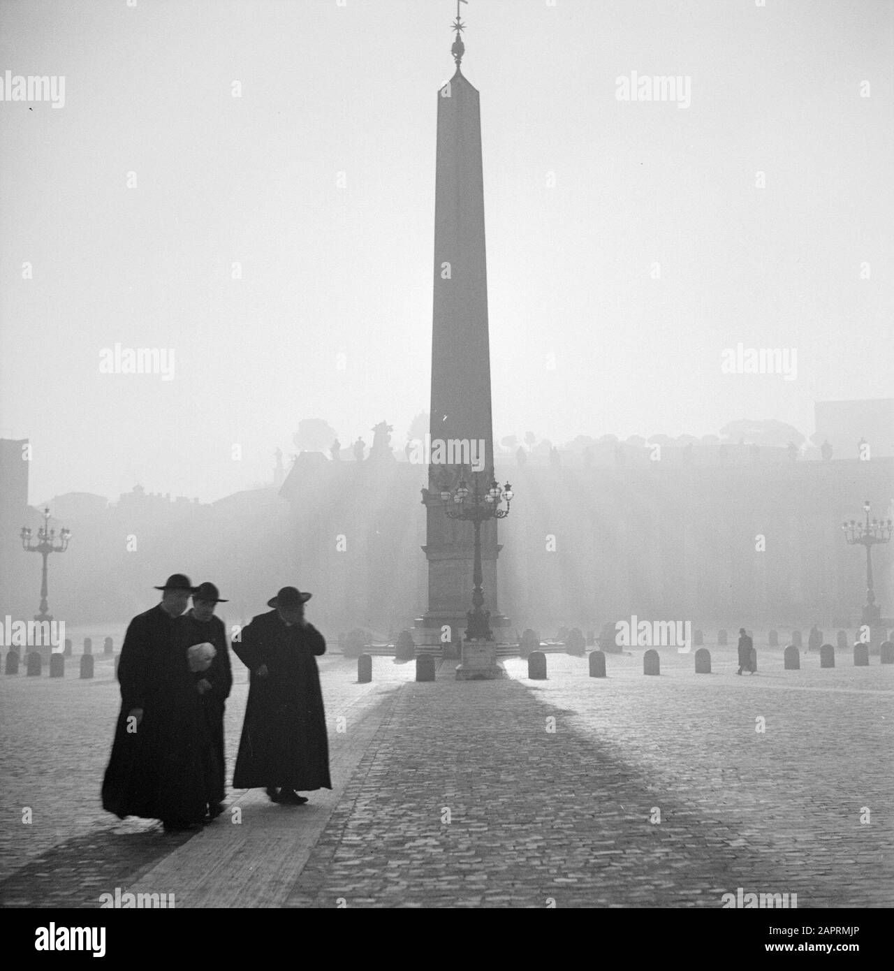 Rome: Visit to Vatican City  Three priest at St. Peter's Square with in the background the Egyptian Obelisk Date: December 1937 Location: Italy, Rome, St. Peter's Square, Vatican City Keywords: fountains, clergymen, Catholicism, obelisks, pillars, squares, city sculptures Institution name: Saint Peter, Vatican Stock Photo