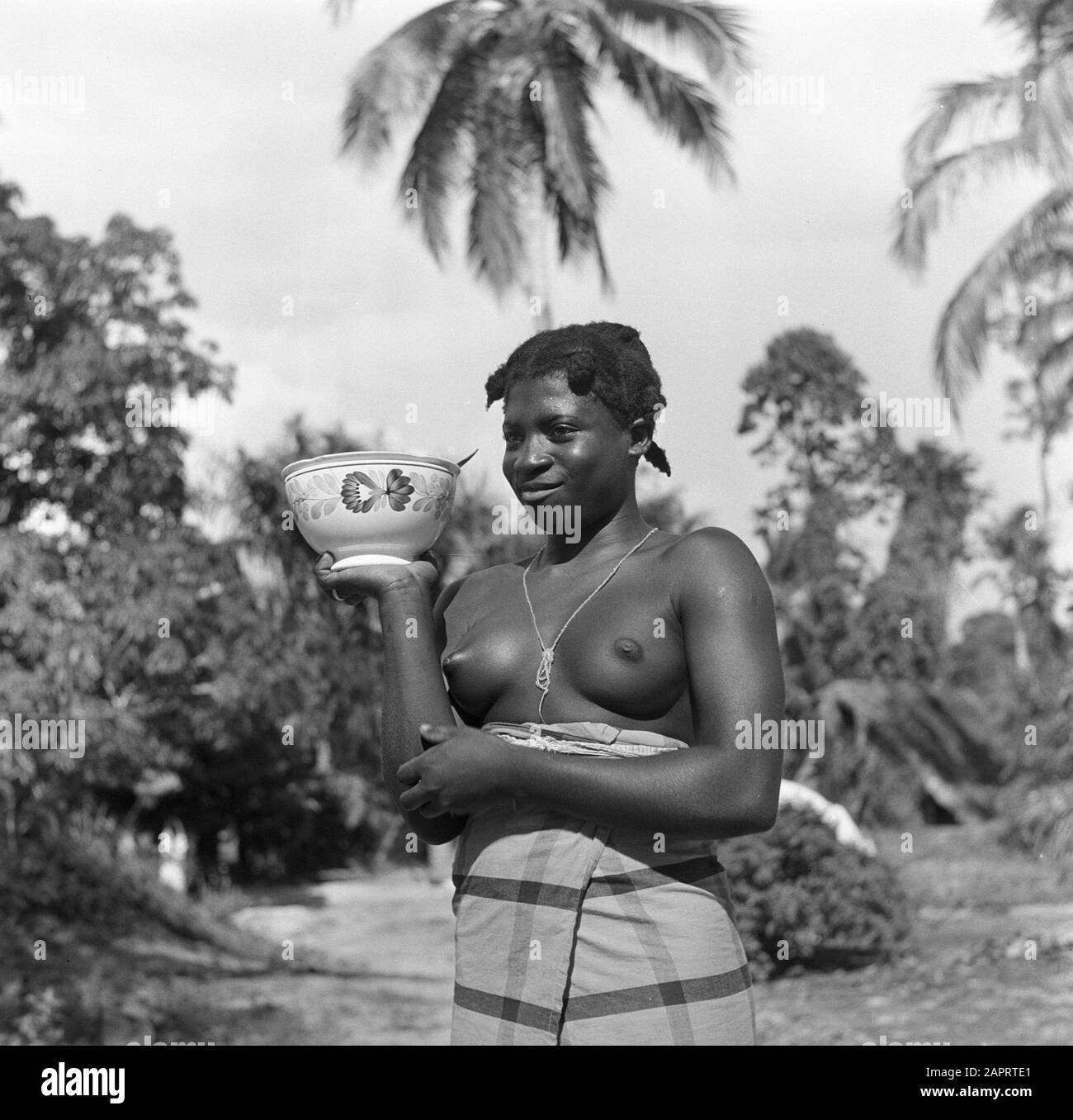 Journey to Suriname and the Netherlands Antilles A forest farm woman in  Ganzee with a bowl of farm fur decor in her hand (Regout, Maastricht?)  Date: 1947 Location: Suriname Keywords: pottery, forest