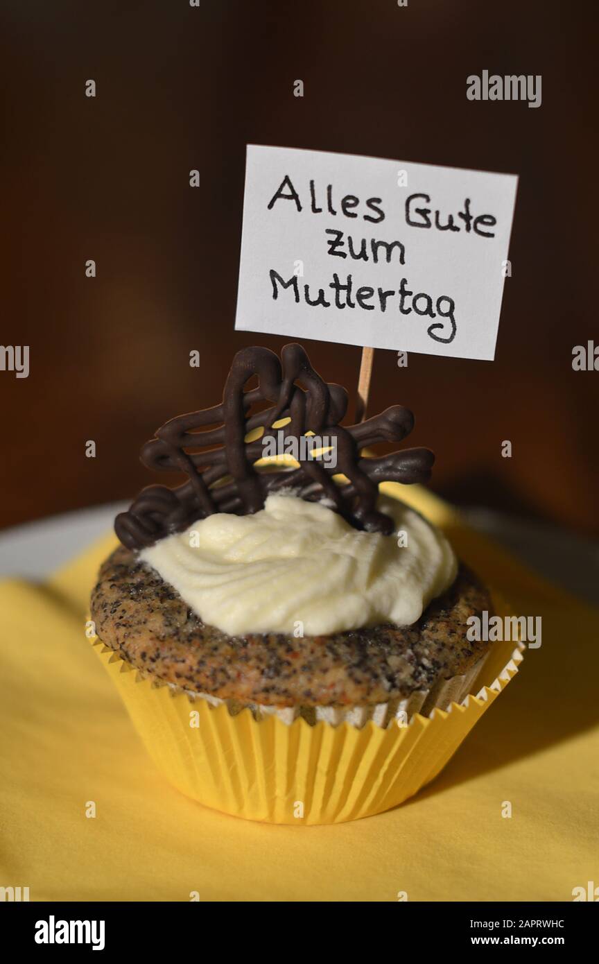 cupcake with a sign saying: ALLES GUTE ZUM MUTTERTAG in German, which means HAPPY MOTHER'S DAY on a plate Stock Photo