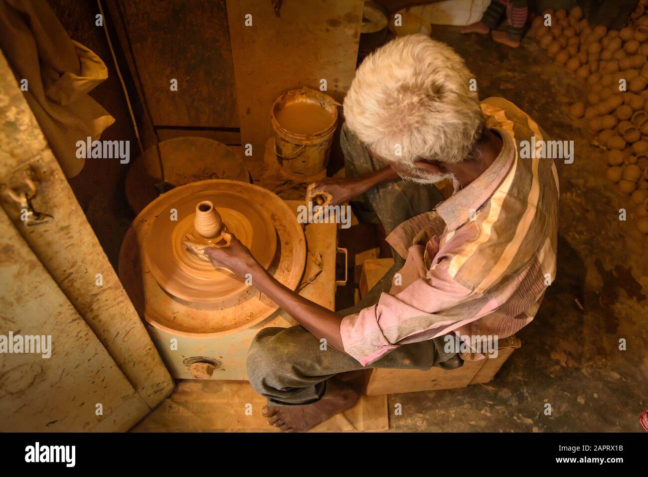 Indian potter making clay pots on pottery wheel in Pottery town is old place. Bangalore. India