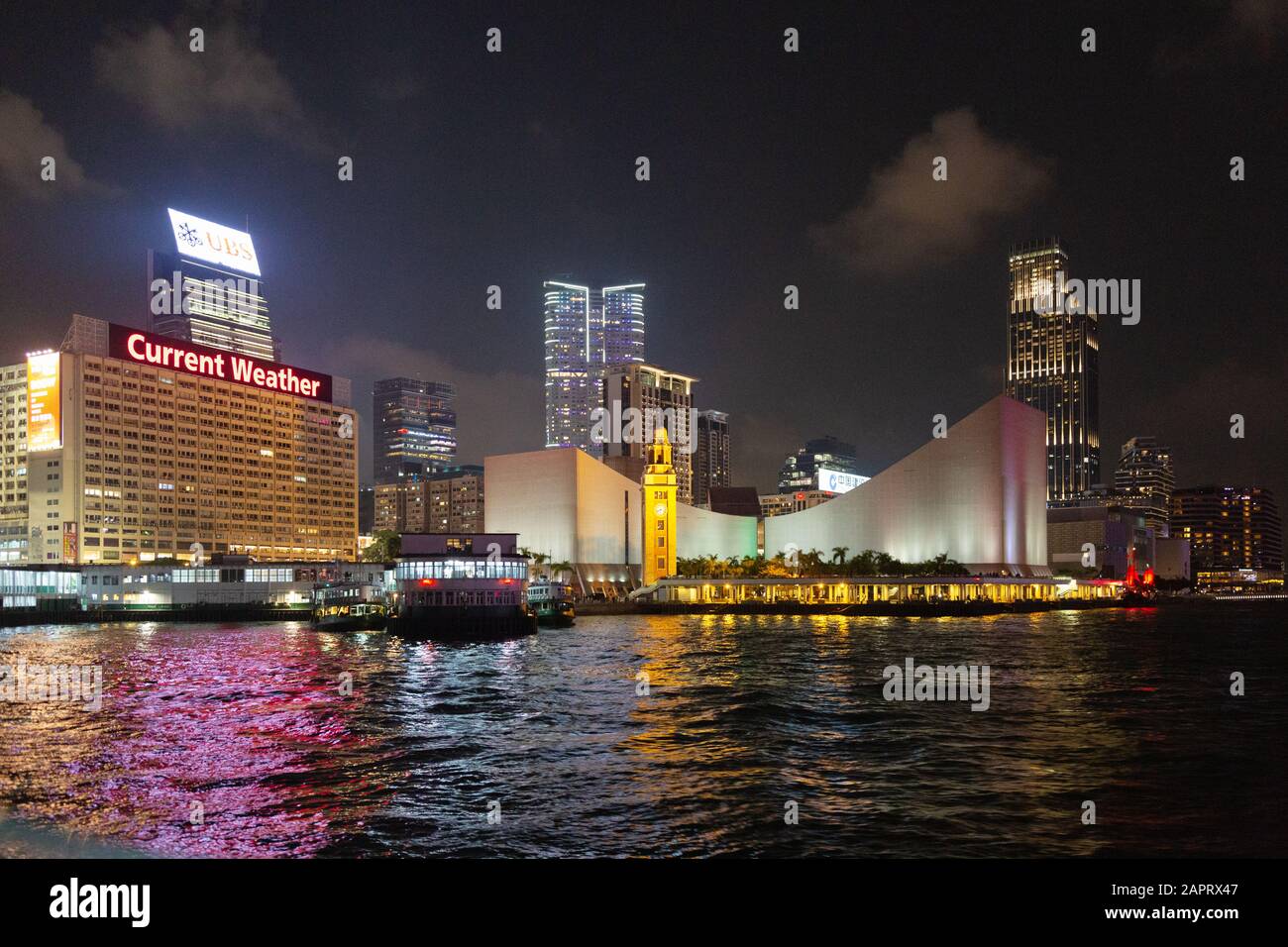 Hong Kong harbour; The Hong Kong Clock Tower and Star Ferry pier, seen from a ferry at night, Tsim Sha Tsui, Kowloon Hong Kong Stock Photo