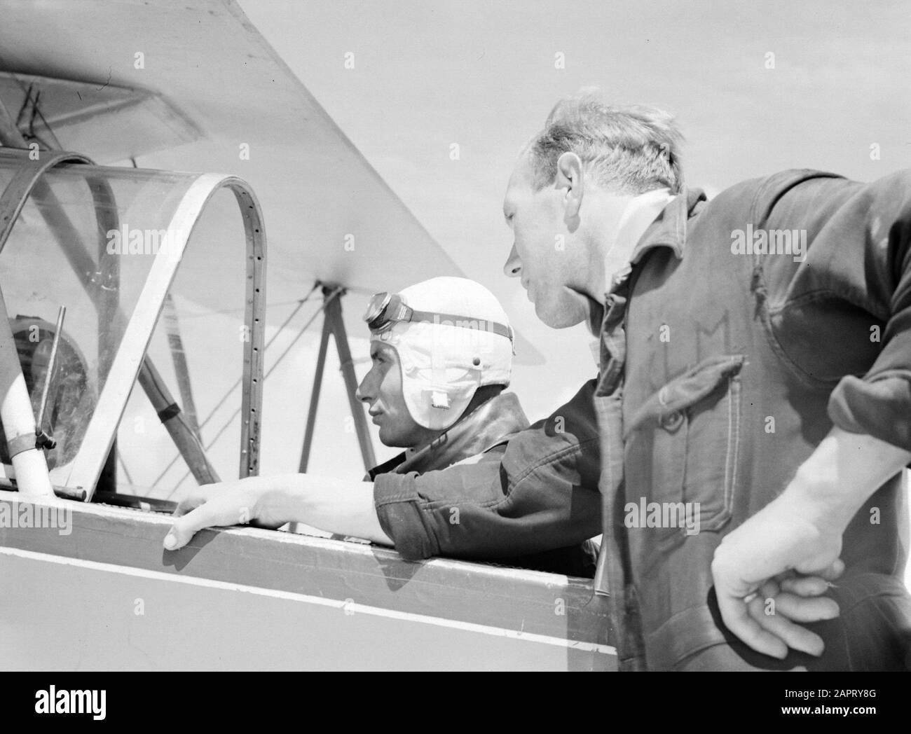 National Aviation School Holland  A mechanic leaning against and an adspirant pilot sitting in a Koolhoven FK-46, because of his docile flight behavior'nicknamed 'Cow or Koebeest of the National Aviation School Amsterdam Schiphol Annotation: The National Aviation School Holland was based in Rotterdam Waalhaven and Amsterdam Schiphol Date: 1933 Location: Amsterdam, Rotterdam Keywords: pupils, mechanics, pilots, flight training, aircraft Personname: Frits Koolhoven Stock Photo